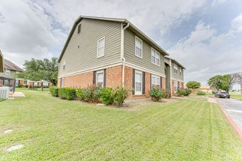 A residential building with a green lawn in front.